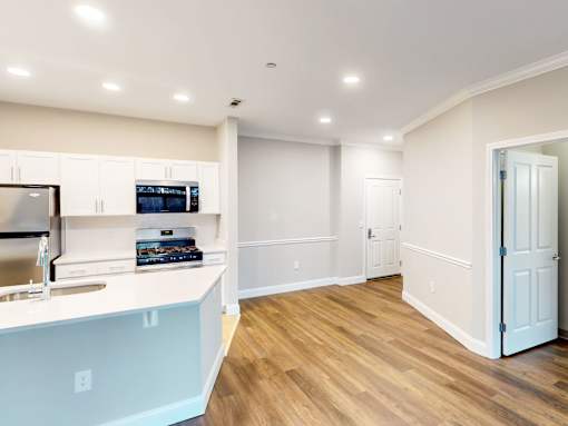 A kitchen with a white counter top and wooden floors.