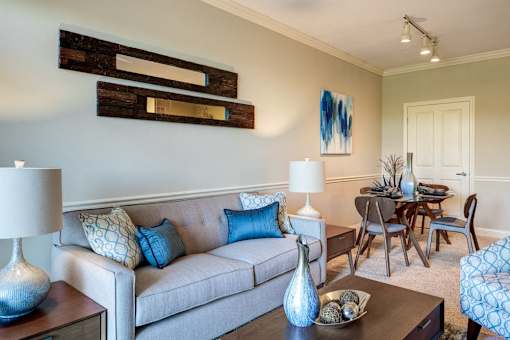 A living room with a grey couch, a coffee table, and a dining table.