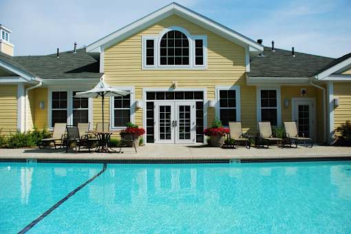 A yellow house with a pool in front.