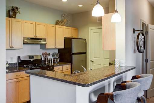 A kitchen with a granite counter top and wooden cabinets.