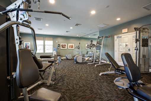 A gym with a variety of equipment including treadmills, weights, and exercise machines.