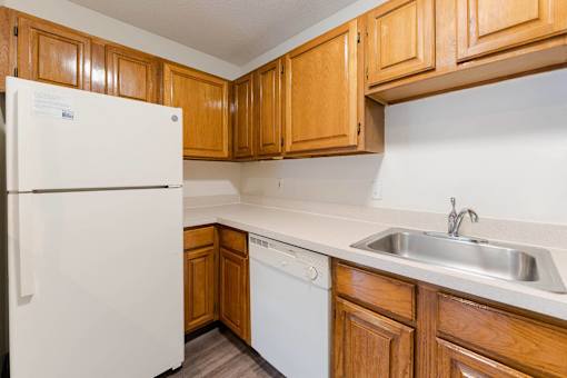 A white refrigerator stands in a kitchen with wooden cabinets.