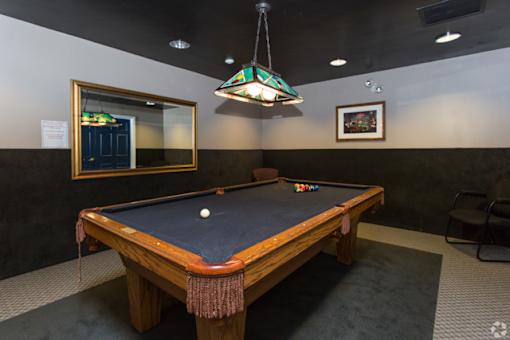 A pool table with a green cloth and a white ball in the middle.