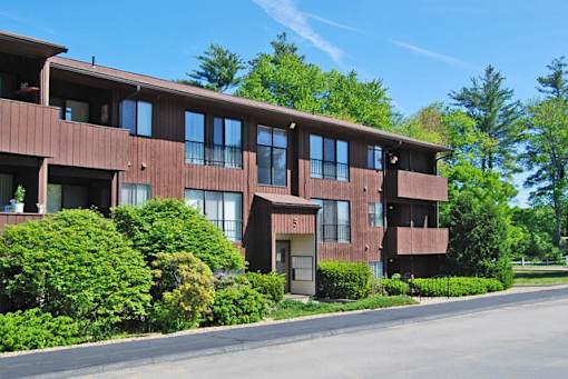 A brown building with green bushes in front.