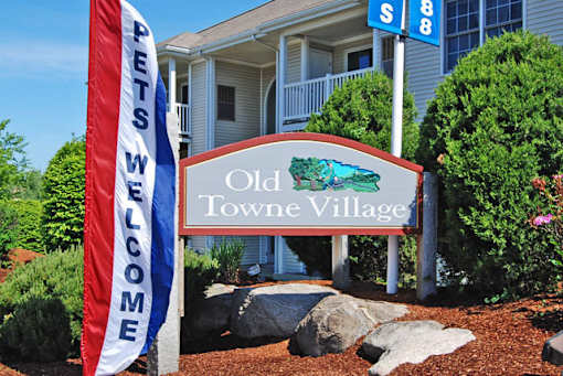 A sign that says Old Towne Village is in front of a house.
