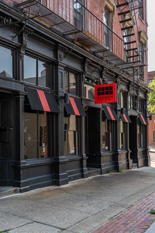 A black building with a red sign that says DENDEN.