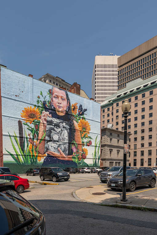 A mural of a person with flowers is painted on a wall.