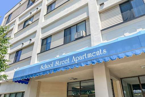 A building with a blue awning that says School Street Apartments.
