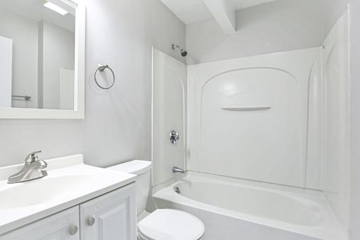 A white bathroom with a toilet, sink, and bathtub.