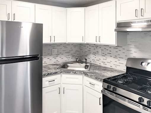 A kitchen with white cabinets and a stainless steel refrigerator.
