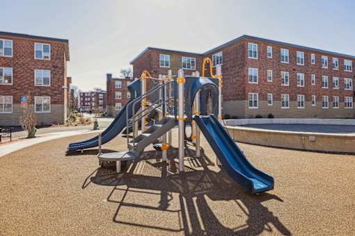 A playground with a blue slide and a yellow and white climbing frame.