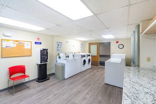 A laundry room with a red chair and washing machines.