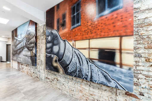 A large mural of a hand is displayed on a brick wall in a spacious room.