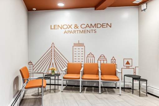 Lenox and Camden Apartments lobby with orange chairs and a cityscape mural.