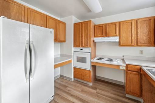 Kitchen with white appliances and wooden cabinets at Monterey Place, Connecticut