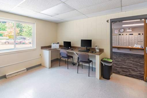 A room with a desk, chairs, and a window.
