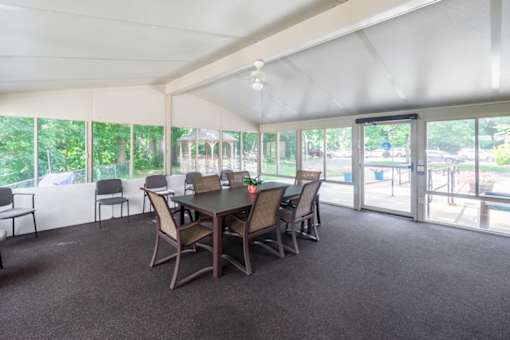 A room with a table and chairs and a ceiling fan.