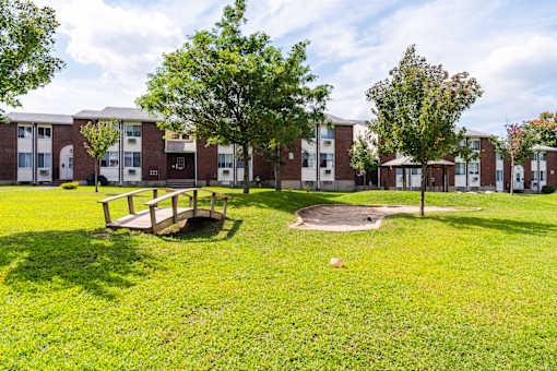 A grassy area in front of a building with a picnic table and a tree at Coppermine Village Apartment, Bristol, CT, 06010