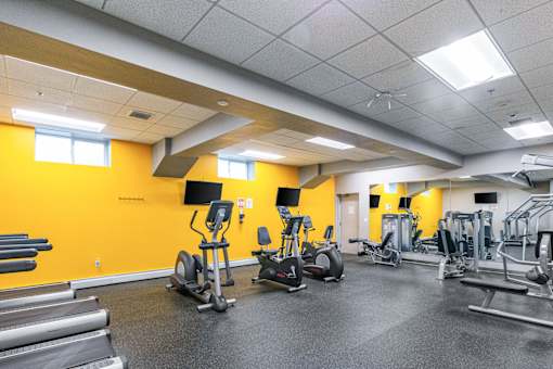 A gym with a variety of equipment including treadmills, weights, and exercise machines at Edmands House, Framingham, 01701