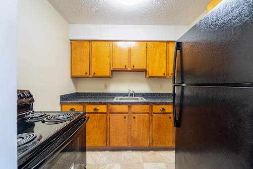 A kitchen with black appliances and wooden cabinets at Coppermine Village Apartment , Bristol