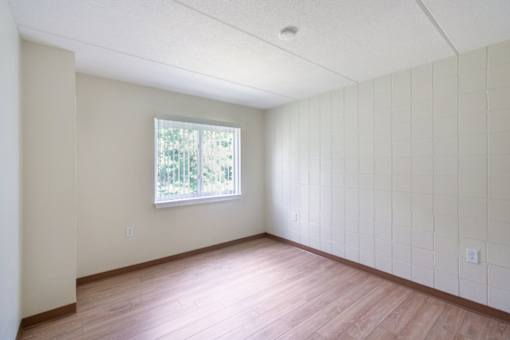 A room with a window and wooden flooring.
