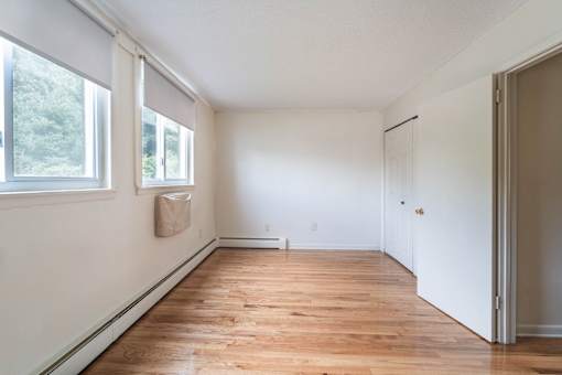 A room with a wooden floor and white walls at Coppermine Village Apartment , Bristol, 06010