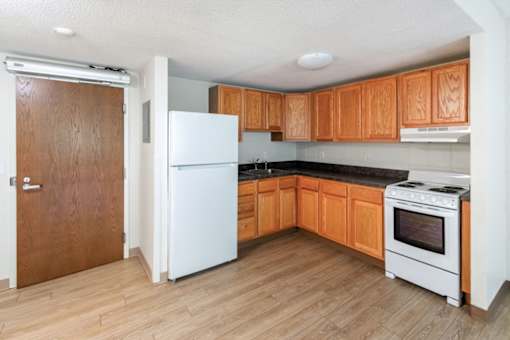 A kitchen with wooden cabinets and a white fridge.