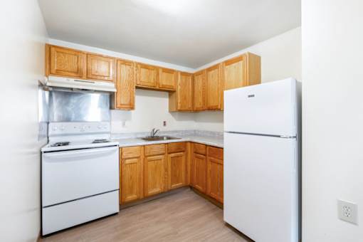 Compact kitchen with white appliances and oak cabinets at Blue Ridge Estates Apartments, Richmond, Virginia