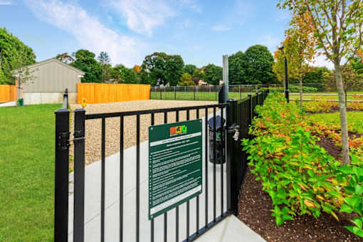 a gate with a sign on it in front of a garden at Beverly Village for Living & the Arts Apartments, Beverly, 01915