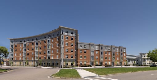 A large brick building with a curved top floor and a parking lot in front. at The Anne M. Lynch Homes at Old Colony, South Boston, Massachusetts