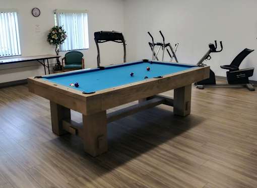 A pool table in a room with exercise equipment.
