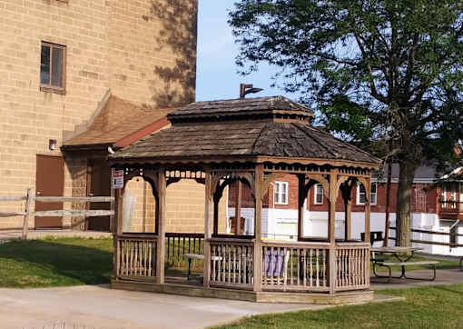 A gazebo with a brown roof is surrounded by a wooden fence.