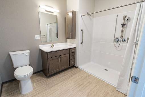 A white toilet sits next to a sink in a bathroom. at 35 Broadway Apartments, Menands