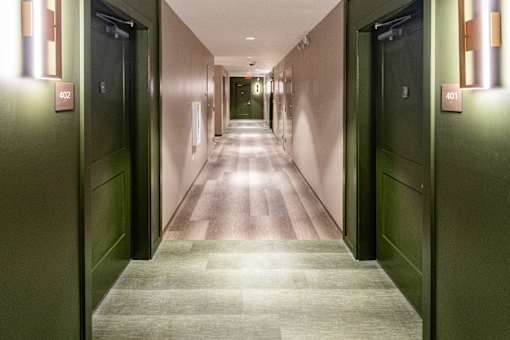 A long hallway with doors on either side and a light on the wall. at 35 Broadway Apartments, Menands, NY