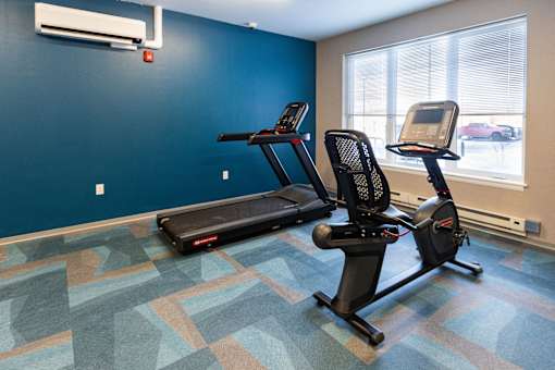 A gym with a treadmill and a stationary bike. at 35 Broadway Apartments, Menands, New York