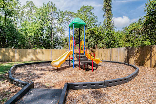 A playground with a yellow slide and a green roof Fishermans Landing Apartments in Ormond Beach, FL.