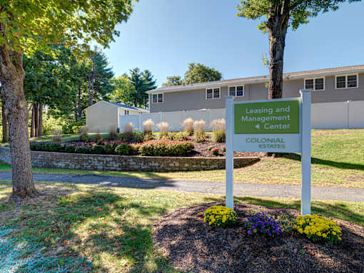 A sign for the Leasing and Management Center of Colonial Estates stands in a landscaped area at Colonial Estates Apartments, Springfield, 01119