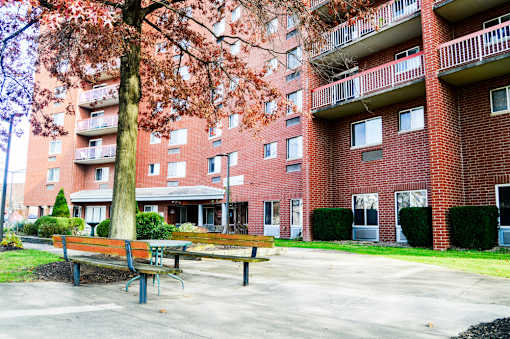 A red brick apartment building with a tree in front of it.