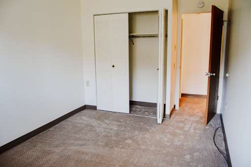 A room with a white door and a brown carpet.