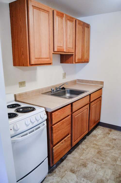 A kitchen with a white stove and wooden cabinets.