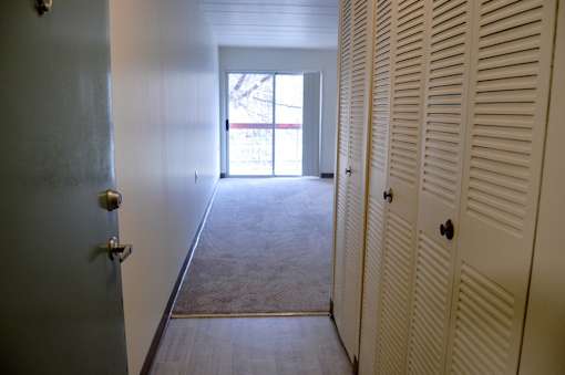 A hallway with a door on the left and a window in the distance.