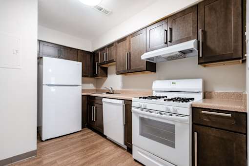 A kitchen with white appliances and brown cabinets.