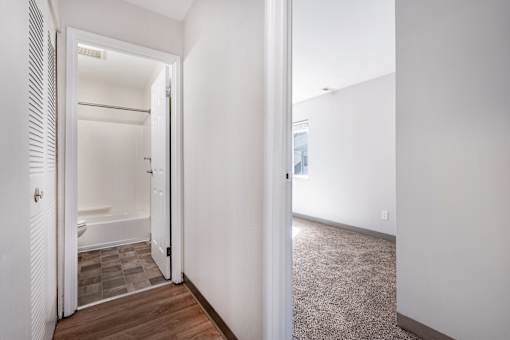 A white hallway with a bathroom visible through the door.