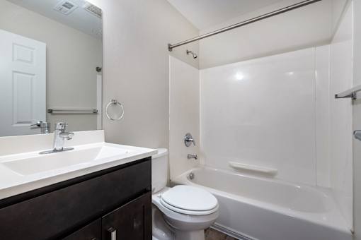 A white toilet sits next to a white bathtub in a bathroom.