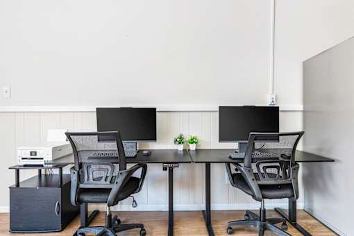 A black chair is placed in front of a black monitor.