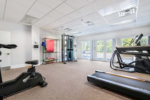 A gym with a treadmill, exercise bike, and other equipment.