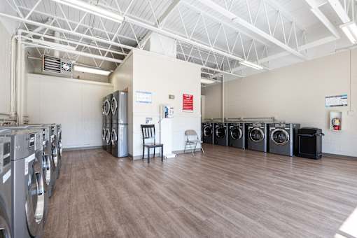 A laundromat with a row of washers and dryers.