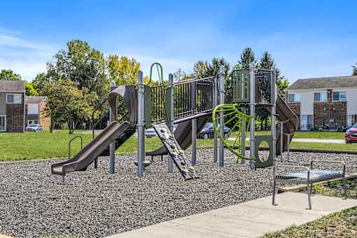 A playground with a green slide and a brown slide.