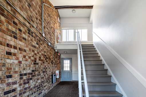 A staircase with a brick wall on one side and a white wall on the other.