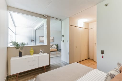 a bedroom with a white bed and a white dresser with a yellow vase on it